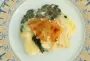 Una capa de puré de patatas sobre una capa de huevos duros, y una capa de espinacas y bacon, unidas con una salsa bechamel.