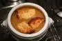Sopa de cebolla, en cocción larga y servida con crutones de queso gratinados.